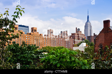 A view of the Empire State and other West Side buildings framed by foliage of The High Line public park in Manhattan, New York. Stock Photo