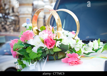 White wedding limousine decorated with flowers and gold rings Stock Photo