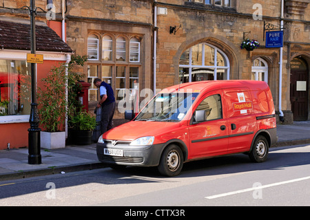 Royal Mail Postman on his route collecting mail from this postbox in Dorset Stock Photo