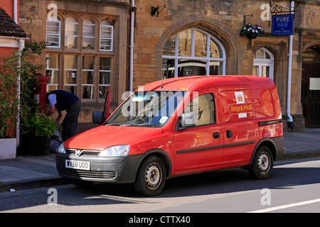 Royal Mail Postman on his route collecting mail from this postbox in Dorset Stock Photo