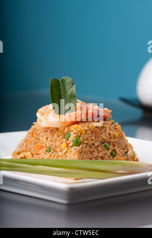 Thai style shrimp fried rice presented on a square white plate in the shape of a pyramid. Stock Photo