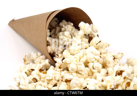 White fluffy tasty popcorn spilling from a brown paper cone isolated on white background with copy space. Stock Photo