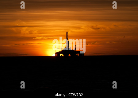 Silhouette of an oil drilling rig in offshore area, during sunset/sunrise time.