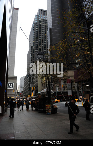 Autumn sidewalk portrait, to 7th Avenue, man holding telescopic squeegee cleaning facade Chase Bank, West 52nd Street, New York Stock Photo