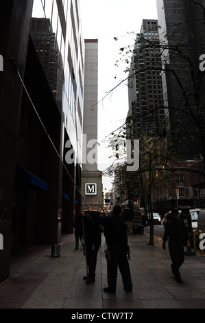 Urban alley sidewalk portrait 2 men with telescopic poles cleaning brown marble facade Chase Bank, West 52nd Street, New York Stock Photo