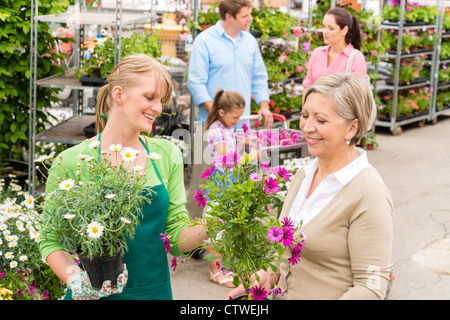 Female florist give advice to senior customer shopping for flowers Stock Photo