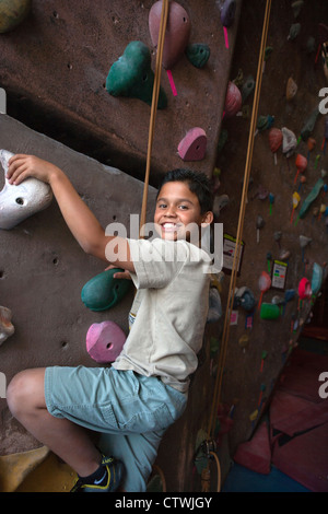 Ten year old Hispanic boy having fun in an indoor rock climbing wall. Stock Photo