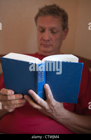 Forty year old man reading Alcoholics Anonymous Big Book. Stock Photo