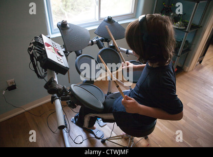 Ten year old boy playing electronic drums at home, wearing headphones. Stock Photo