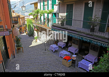 The narrow picturesque street of Salita Serbelloni Bellagio Lake Como Italy with an Italian restaurant and outdoor tables Stock Photo