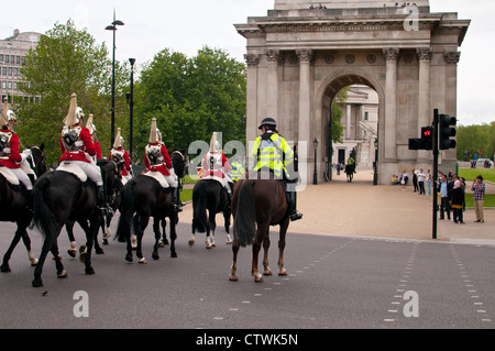 Horse Guards with police escort crossing the road at Hyde Park Corner, London. Stock Photo