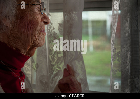 Elderly woman looking out of window Stock Photo