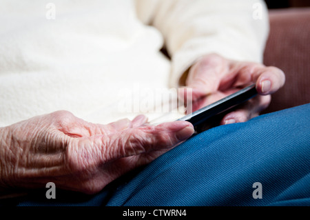 Close-up of elderly woman's hands texting and using apps on her iPhone smartphone Stock Photo