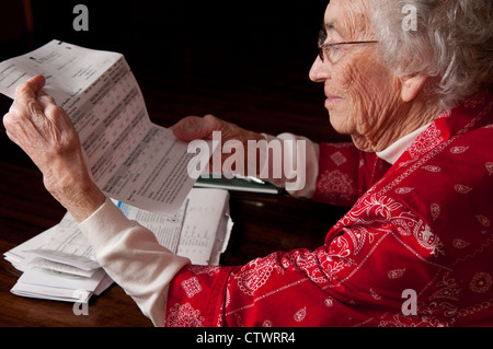 Elderly woman reading through bills and financial paperwork Stock Photo