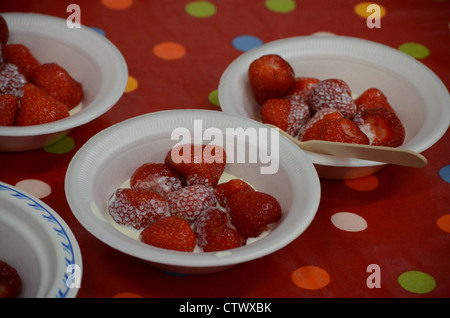 Bowls of strawberries and cream on red spotted tablecloth Stock Photo