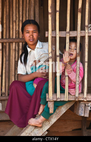 Women of the AKHA tribe nurses a child in her bamboo house - village near KENGTUNG or KYAINGTONG - MYANMAR Stock Photo