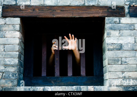 Prisoner hands stretch out from prison bars Stock Photo