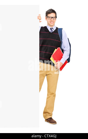 Full length portrait of a male student posing behind a blank panel isolated on white background Stock Photo