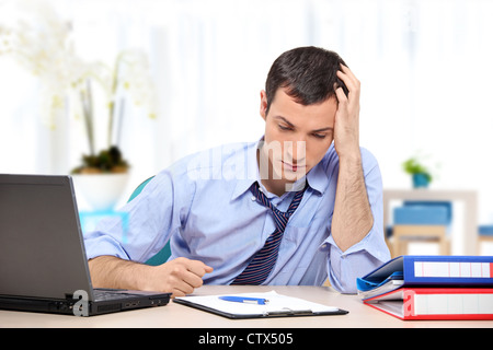 A young desperate businessman in his office looking down Stock Photo