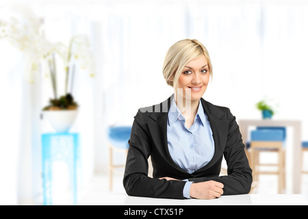 A blond smiling businesswoman sitting at her desk