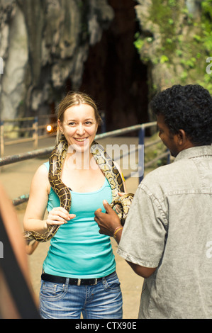 a caucasian woman tourist posed with snake in batu cave, kuala lumpur, malaysia. Stock Photo