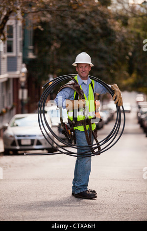 Cable installer carrying video cables on a street Stock Photo