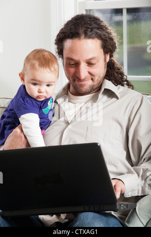 Father and baby looking at computer at home Stock Photo