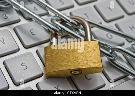 A computer keyboard wrapped in and locked with a padlock and chain. Stock Photo