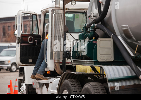 Environmental engineer reaching in driver's side of tanker truck for hazardous waste cleanup Stock Photo