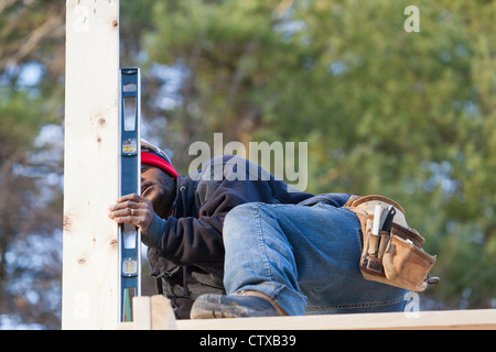 Carpenter using a level to measure vertical roof support Stock Photo