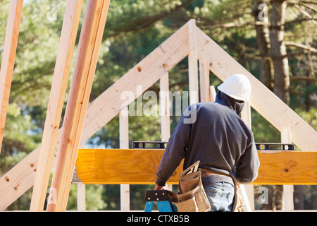 Carpenter using horizontal level on beam Stock Photo