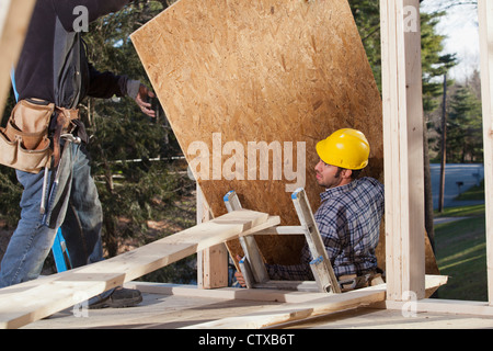 Carpenter bringing particle board to upper level Stock Photo