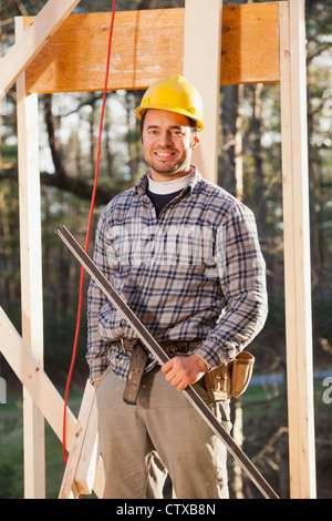 Portrait of a carpenter holding a level on house framing Stock Photo