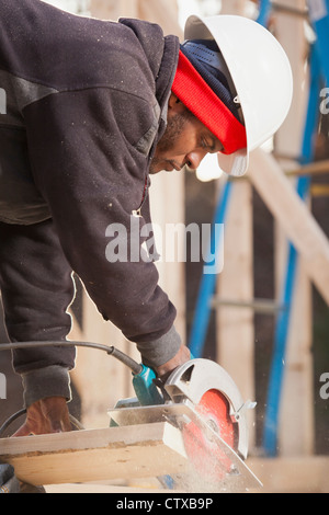 Carpenter using a circular saw for cutting rafter Stock Photo