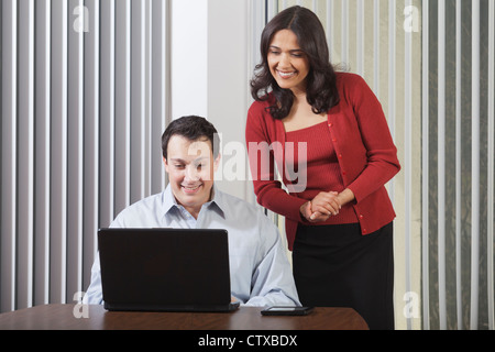 Hispanic businesswoman and businessman looking at computer Stock Photo