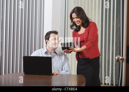 Hispanic businesswoman and businessman in office with tablet and computer Stock Photo