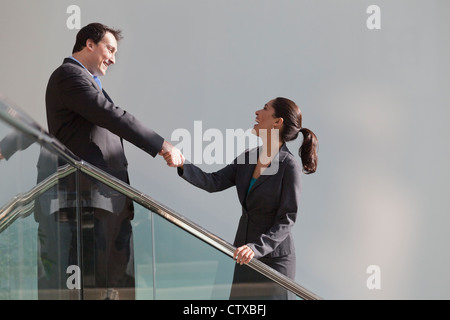 Hispanic businesswoman shaking hands with businessman on stairwell in office building Stock Photo