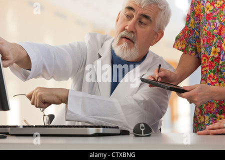 Doctor and nurse in conference with computer and tablet Stock Photo