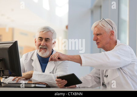 Two doctors discussing information on a computer and a tablet Stock Photo