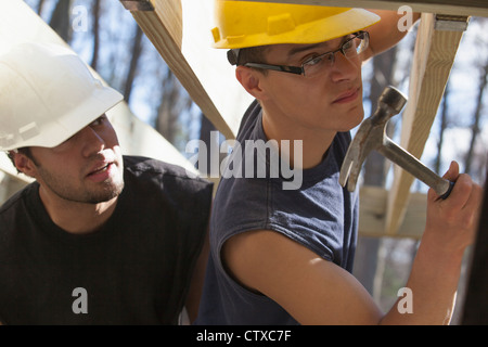 Hispanic carpenters using hammer on deck joist supports Stock Photo