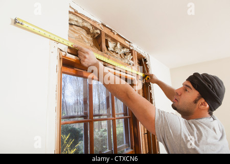 Hispanic carpenter measuring framing over window during home renovation Stock Photo