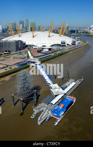 Aerial view of North Greenwich Peninsula & Pier Thames Clipper river bus beside O2 arena millenium dome 2000 & Canary Wharf skyline beyond London UK Stock Photo