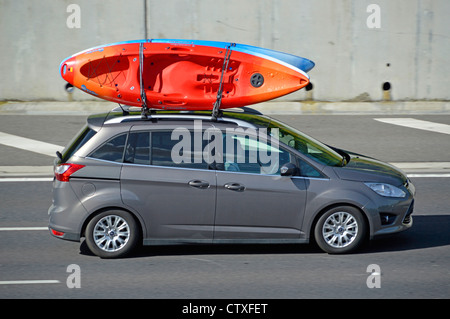 Car driving along with transporting canoe kayaks on roof rack Stock Photo