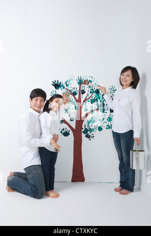 A family painting the tree on the wall Stock Photo