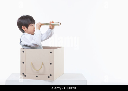 A boy looking through the telescope in the box Stock Photo
