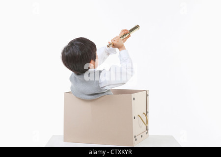 A boy looking through the telescope in the box Stock Photo