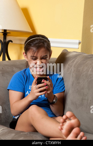 10 year-old Japanese-American girl uses mobile i-phone to call and text friends while relaxing at home Stock Photo
