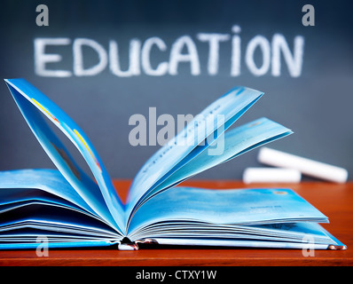 Education concept, open book on the desk in the classroom, chalkboard with education word, back to school Stock Photo