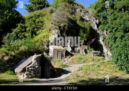 A visitor emerges from one of the restored Chinese gold mines, part of the Chinese Settlement in the old gold mining museum in Arrowtown, Otago, New Stock Photo