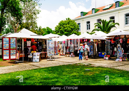 Tourists looking around well stocked and colourful souvenir stalls on a stone paved terrace in Santa Maria de Belem, Lisbon Stock Photo